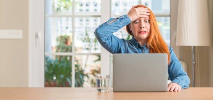 Une femme rousse voit une erreur sur sa déclaration de revenus pré-remplie par une plateforme de crowdfunding
